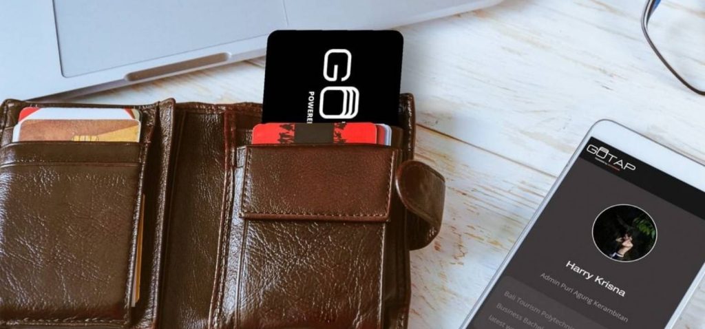 smart business card in the leather wallet between MacBook and iPhone on the white woody desk