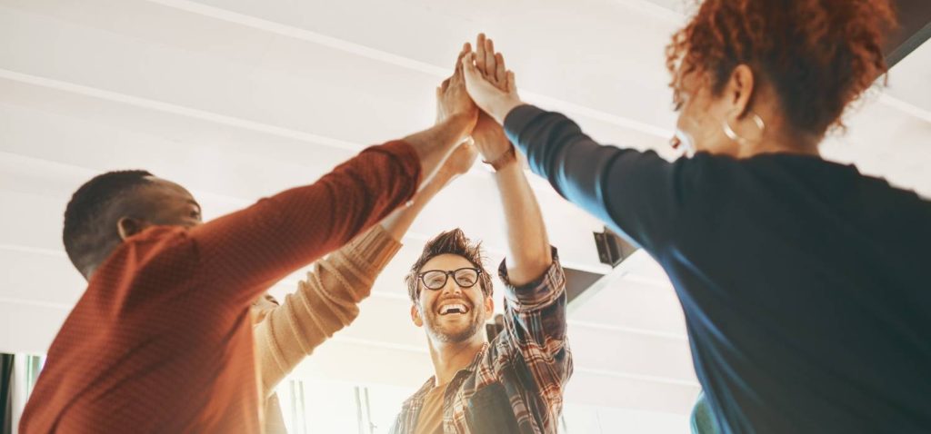 three people high five together with casual uniform in the office