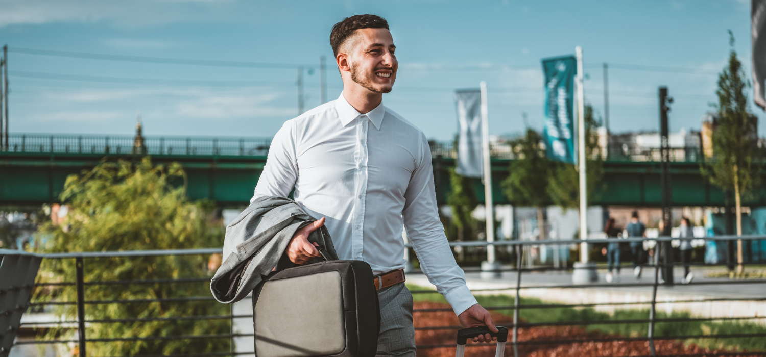 A male businessman happily holding his suitcase on his business trip