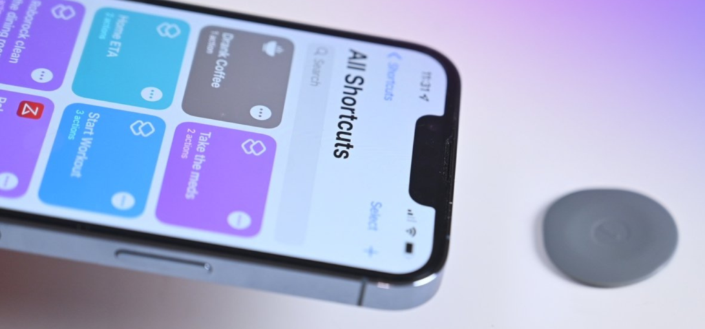 Jari seseorang memegang iPhone 14 untuk mendekatkannya ke NFC Smart Tag GOTAP di atas meja putih dan gradien ungu sebagai latar belakang