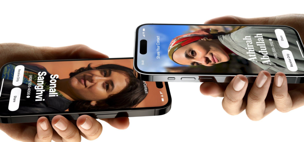 Two women use their own hands to hold their iPhone 15 closely and activate NameDrop so they can share each other contact. 