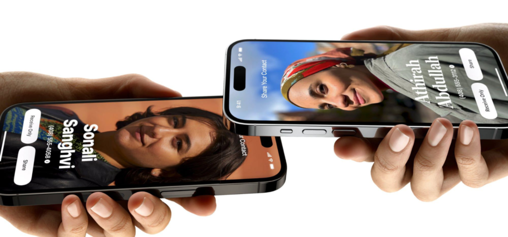 Dua wanita memegang erat iPhone 15 mereka dan mengaktifkan NameDrop sehingga meareka dapat saling berbagi kontak.
